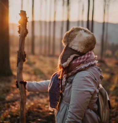 a woman in a forest with sunset in the background